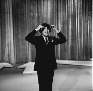 Ed Sullivan wears a "Beatles" wig on the stage of his variety show during The Beatles first ever live U.S. television performance. Photo by CBS/Getty Images