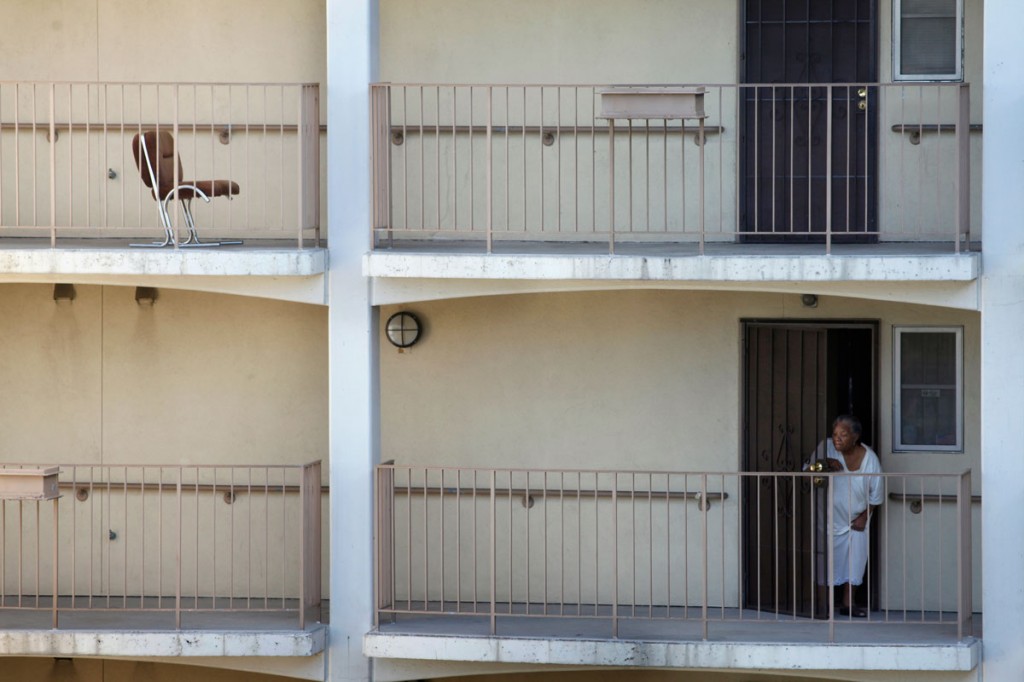 A resident peeks out her front door after hearing yelling in the courtyard at the Hacienda housing complex. Hacienda has paid security guards, but some have admitted that the place intimidates them. Photo by Lacy Atkins/San Francisco Chronicle