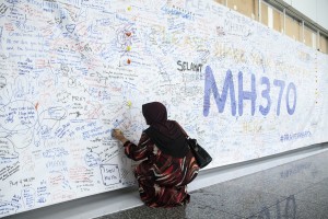 A woman writes a message on a banner for missing Malaysian Airlines Flight 370 at Kuala Lumpur International Airport (KLIA) in Sepang, Malaysia, in March 2014. Photo by Charles Pertwee/Bloomberg