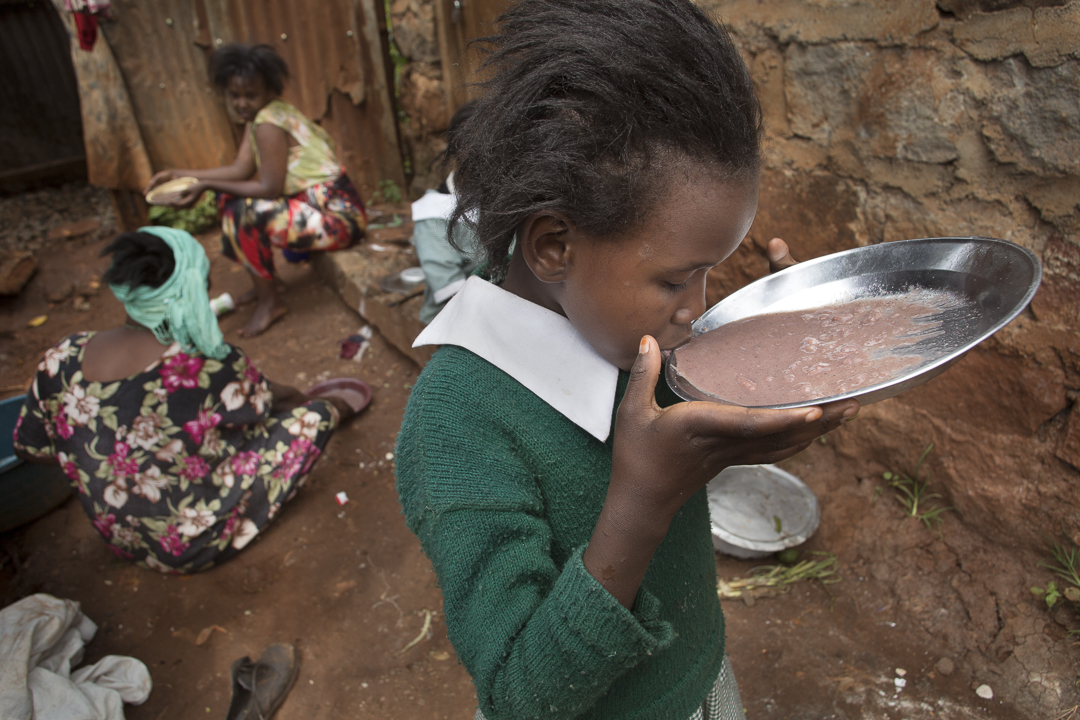A girl sips porridge in Nairobi, Kenya. In urban areas, getting food is a challenge particularly for refugee families. Photo by Amy Toensing
