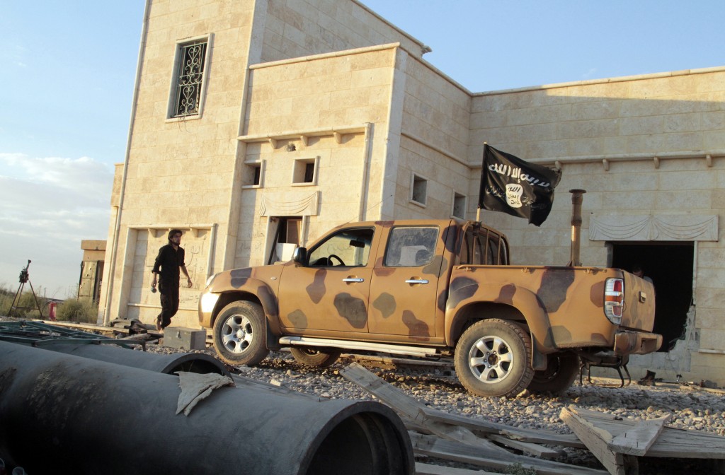 An opposition fighter walks near a vehicle flying a black Jihadist flag in the northern rebel-held Syrian city of Raqqa on Oct. 6, 2013. Photo by Mohammed Abdul Aziz/AFP/Getty Images