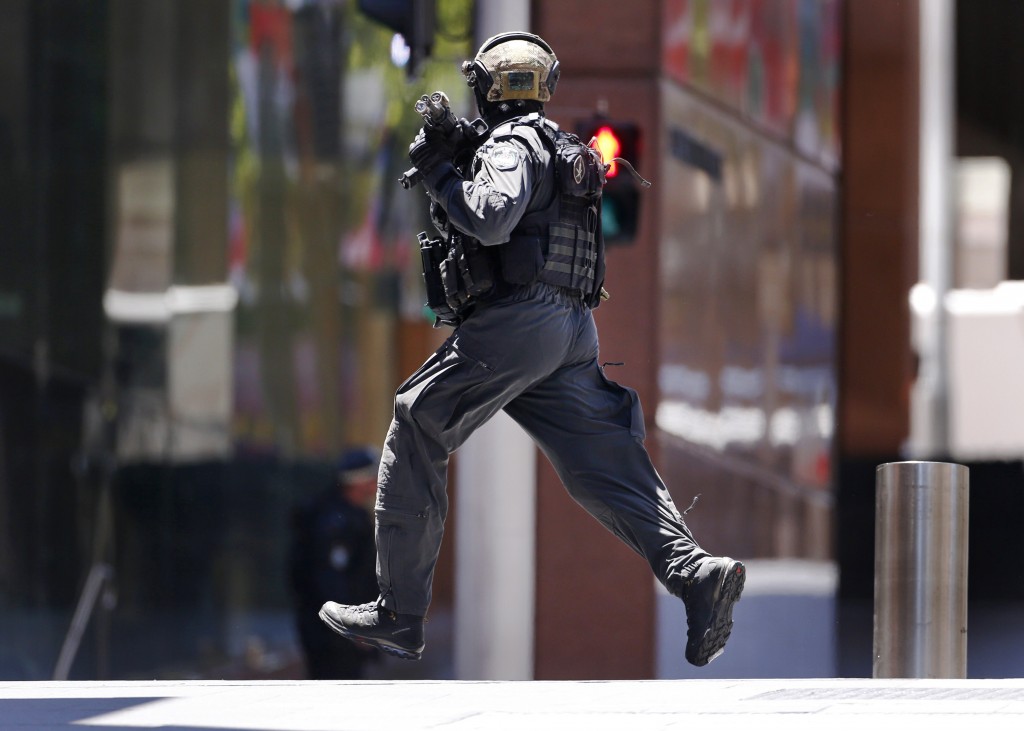 A police officer runs across Martin Place near Lindt cafe, where hostages are being held, in central Sydney December 15, 2014. Hostages were being held inside the central Sydney cafe where a black flag with white Arabic writing could be seen in the window, local television showed on Monday, raising fears of an attack linked to Islamic militants.       REUTERS/David Gray (AUSTRALIA - Tags: CRIME LAW CIVIL UNREST) - RTR4HZRY