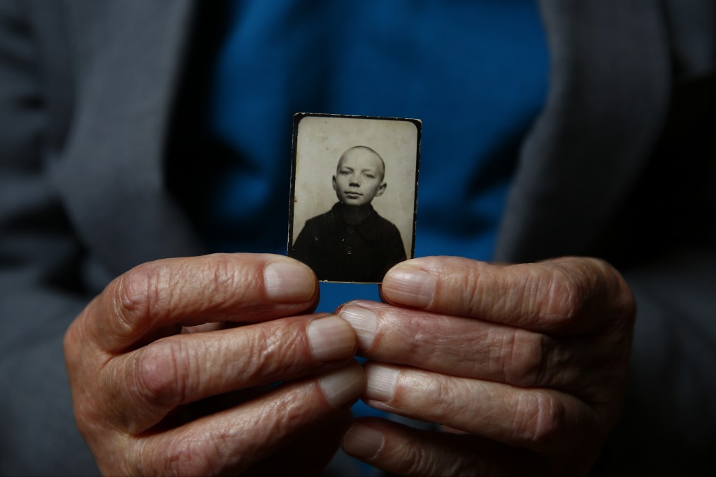 Auschwitz concentration camp survivor Stefan Sot holds a picture of himself taken during the war, in Warsaw