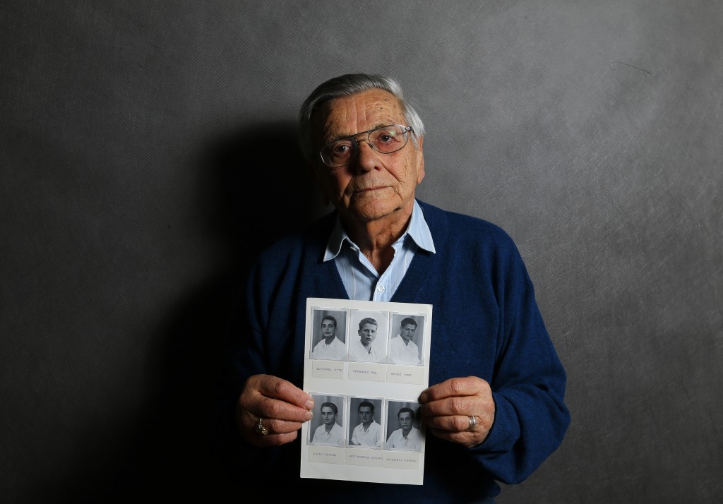 Auschwitz death camp survivor Imre Varsanyi holds up a photo of his fellow survivors during World War II as he poses for a portrait in Budapest