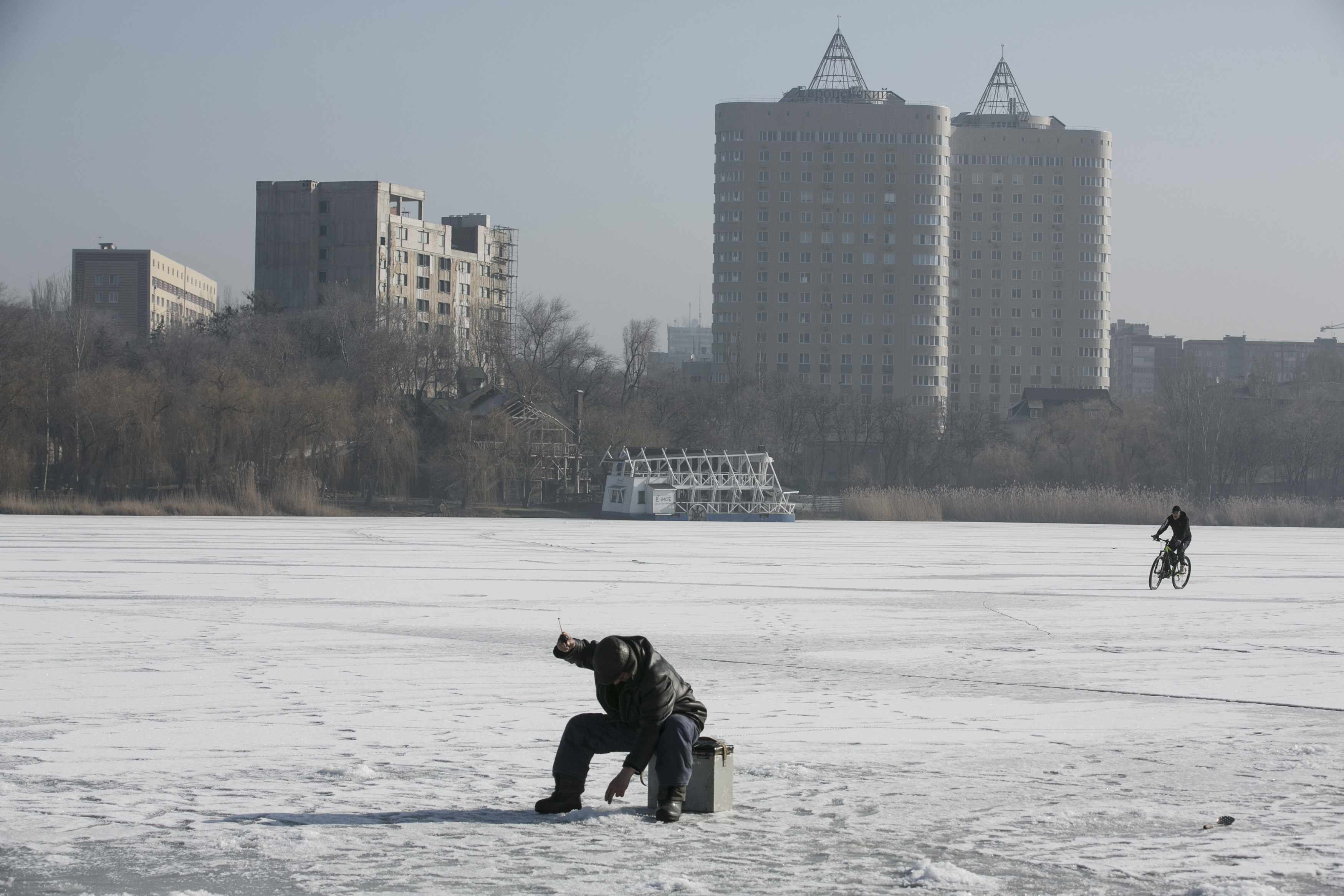 A man fishes through an ice hole on a frozen river in Donetsk, Ukraine, February 15, 2015.  Photo by Baz Ratner/Reuters