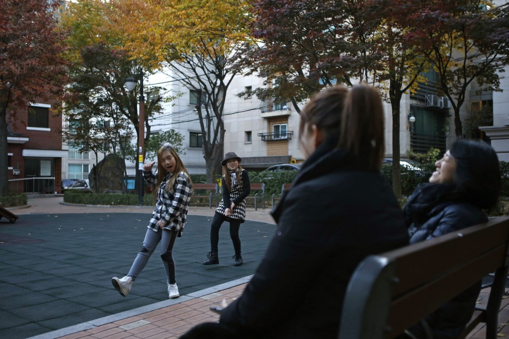 Kim Si-yoon and Yoo Ga-eul, left, dance in front of their mothers as they play at a playground in Seoul November 15, 2014. Photo by Kim Hong-Ji/Reuters