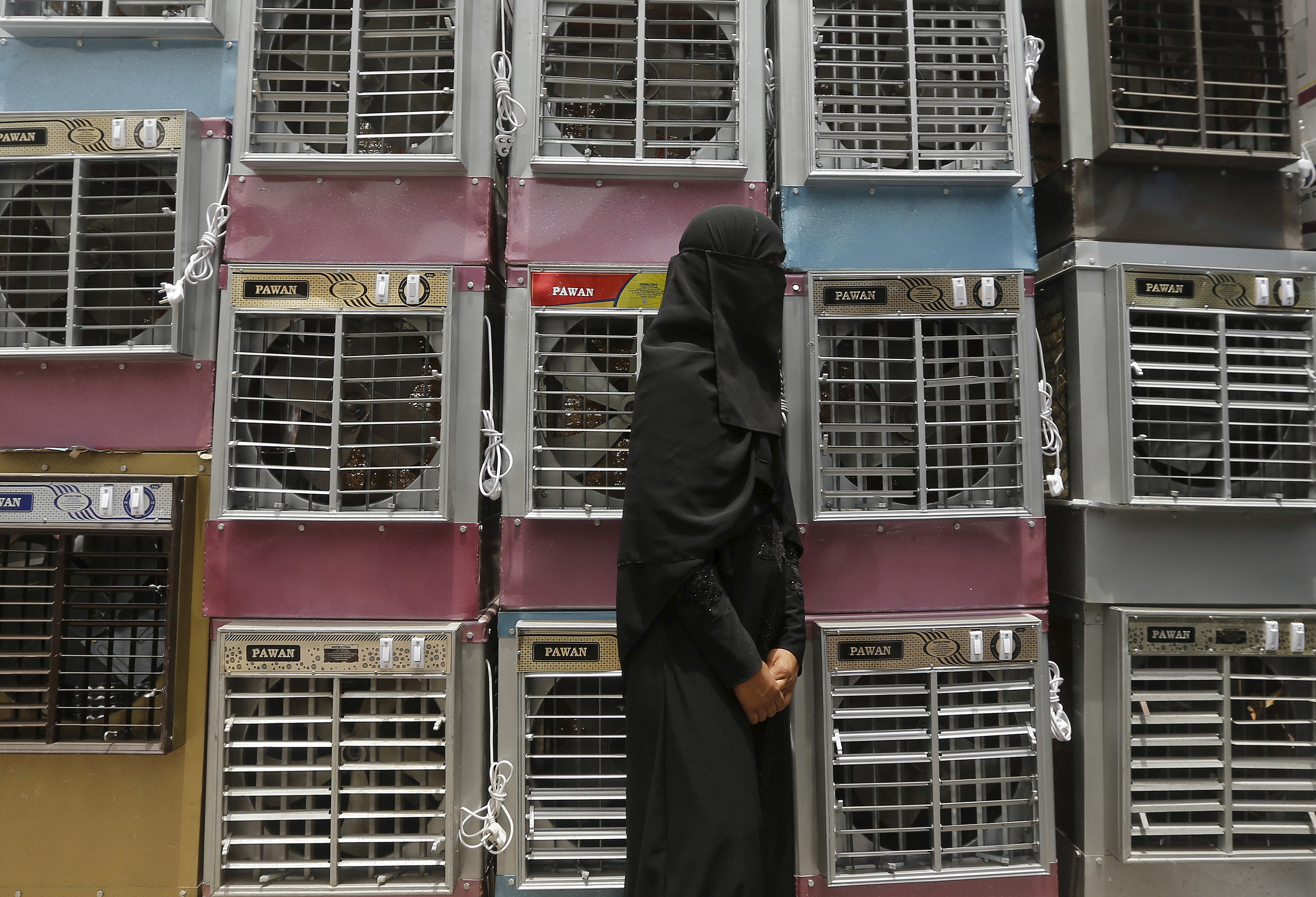A customer stands beside stacked air coolers kept for sale at a shop in New Delhi, India, May 28, 2015. Photo by Adnan Abidi/Reuters