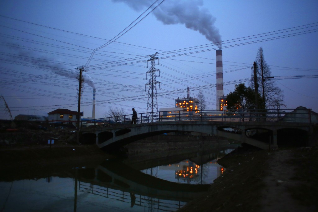 A man walks over a bridge as smoke rises from chimneys of a thermal power plant in Shanghai February 23, 2015. Nearly 90 percent of China's big cities failed to meet air quality standards in 2014, but that was still an improvement on 2013 as the country's "war on pollution" began to take effect, the environment ministry said on February 2, 2015. REUTERS/Carlos Barria  (CHINA - Tags: ENERGY ENVIRONMENT) - RTR4QT9B