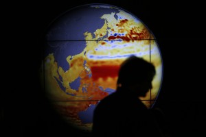 A woman walks past a map showing the elevation of the sea in the last 22 years during the World Climate Change Conference 2015 (COP21) at Le Bourget, near Paris, France, December 11, 2015. Photo by Stephane Mahe/REUTERS