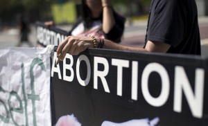 An activist holds a rosary while ralling against abortion outside City Hall in Los Angeles