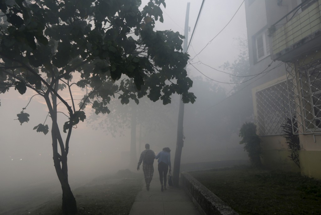 People walk among clouds of insecticide after a fumigating truck moved past in Havana March 1, 2016. Cuba conducts regular fumigation inside homes to check the spread of dengue, a virus transmitted by the Aedes aegypti mosquito that causes a fever which can be deadly. The same mosquito can also spread the Zika virus, although the Cuban government says there have been no reported cases of the disease in the country. Enrique de la Osa/Reuters