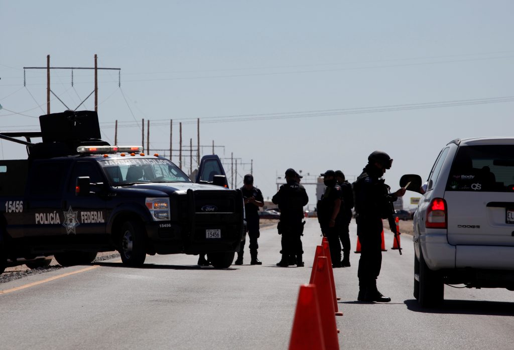 A federal police officer (R) inspect a vehicle at a security checkpoint near a prison in Ciudad Juarez where Mexican drug boss Joaquin "Chapo" Guzman has been moved from his jail in central Mexico May 7, 2016. Photo By Jose Luis Gonzalez/Reuters 