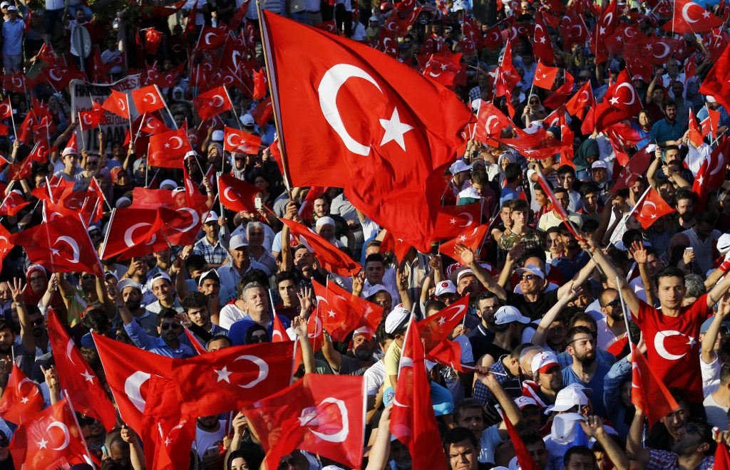 People wave flags as they wait for Turkish President Tayyip Erdogan to appear for a speech in Istanbul, Turkey, July 16, 2016. REUTERS/Murad Sezer - RTSIAZH