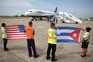 Ground crew hold U.S. and Cuban flags near a recently landed JetBlue aeroplane, the first commercial scheduled flight between the United States and Cuba in more than 50 years, at the Abel Santamaria International Airport in Santa Clara, Cuba, August 31, 2016. Photo by Alexandre Meneghini/REUTERS