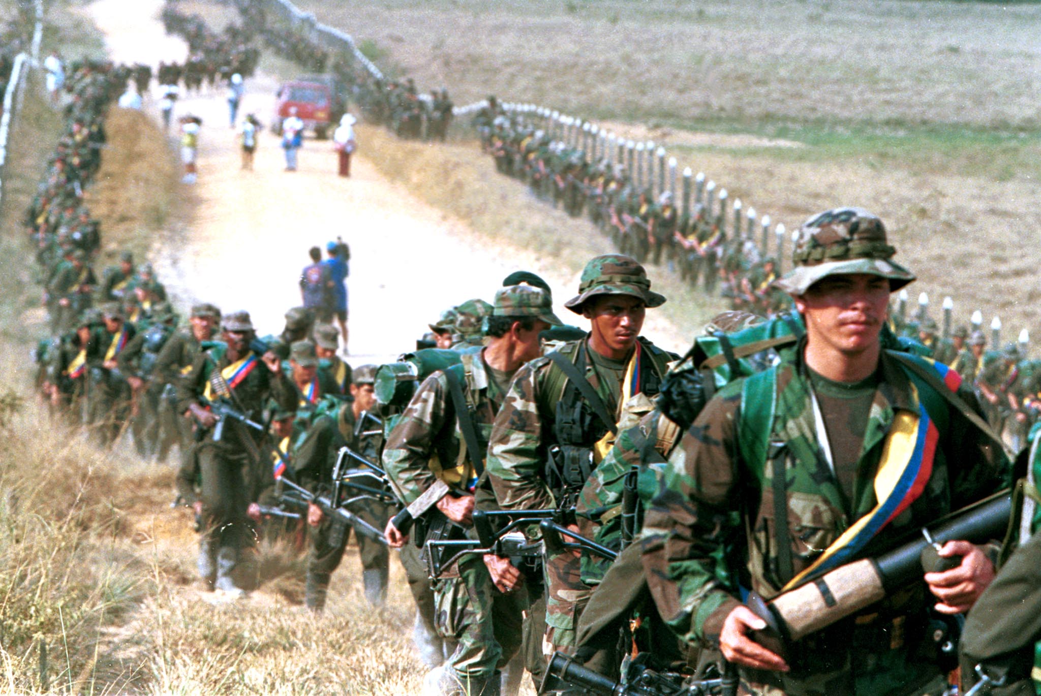 Rebels of the Revolutionary Armed Forces of Colombia (FARC) patrol by a roadway near to San Vicente de Caguan January 9, 1999. More than 200,000 people have been killed in the 52-year conflict. Photo By Reuters 