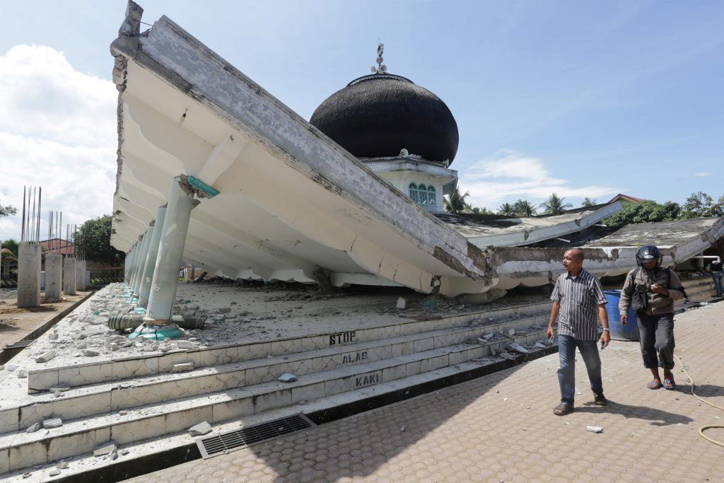 People walk near a collapsed mosque following a Dec. 7 earthquake in Meuredu, Pidie Jaya in the northern province of Aceh, Indonesia.  Antara Foto/ Irwansyah Putra/via REUTERS