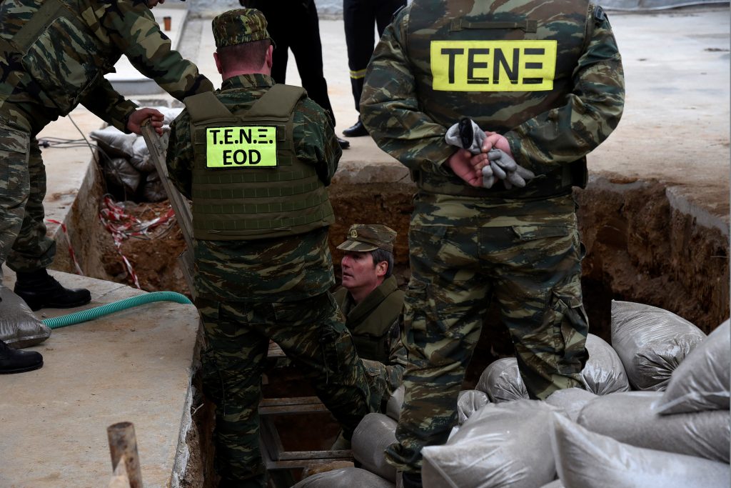 A military officer (C) of the Hellenic Army's Explosives Ordnance Disposal (EOD) is seen inside a hole in the ground where a 250 kg World War Two bomb was found during excavation works at a gas station, before an operation to defuse it, in the northern city of Thessaloniki, Greece, February 12, 2017.  REUTERS/Alexandros Avramidis - RTSY8W8