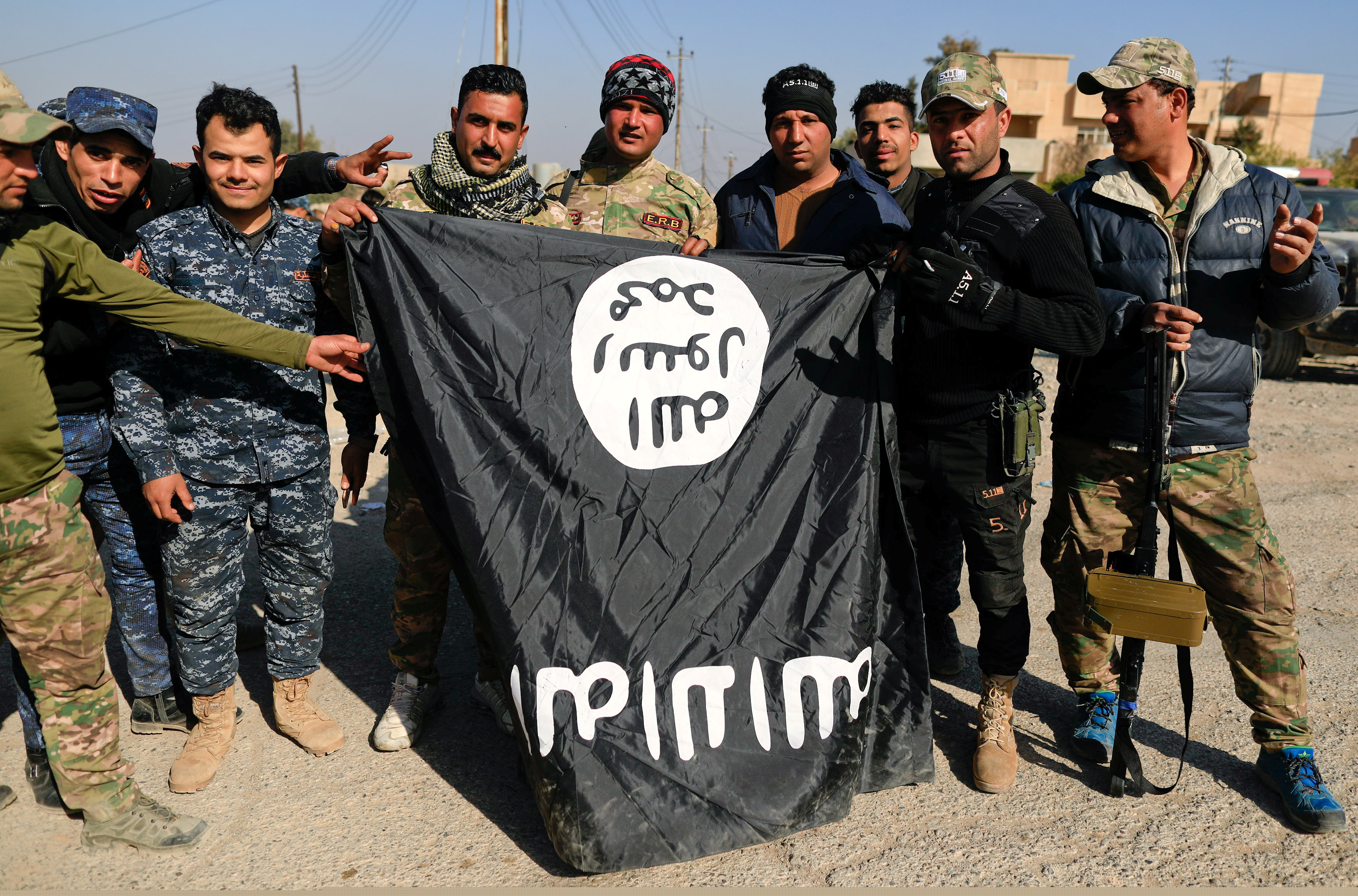 Iraqi security forces pose with a seized Islamic State flag after driving out miitants from Mosul's airport. Photo by Zohra Bensemra/Reuters