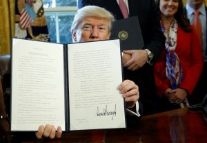 After signing, President Donald Trump holds up an executive order rolling back regulations from the 2010 Dodd-Frank law on Wall Street reform at the White House in Washington, D.C. Photo by Kevin Lamarque/Reuters