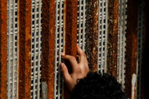 A man, who was deported from the U.S. seven months ago, touches the fingertips of his nephew across a fence separating Mexico and U.S, as photographed from Tijuana