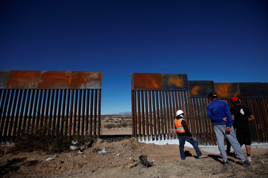 A worker chats with residents at a newly built section of the U.S.-Mexico border fence at Sunland Park, U.S. opposite the ...
