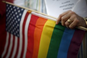 A married gay man carries the rainbow and U.S. flags at a celebration rally in West Hollywood, California, following the 2015 Supreme Court decision on marriage equality. Photo by Nicholson/Reuters