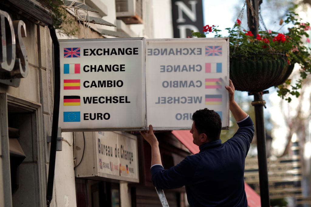 A worker places a sign of a money changing shop in the British overseas territory of Gibraltar