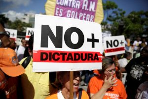 An opposition supporter holds a placard that reads "No more dictatorship" as she takes part in a rally against Venezuela's President Nicolas Maduro's government in Caracas