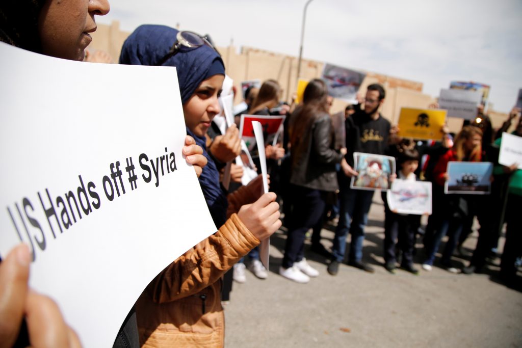 People attend a protest against American airstrikes in Syria, in front of the United Nations (UN) building in Damascus