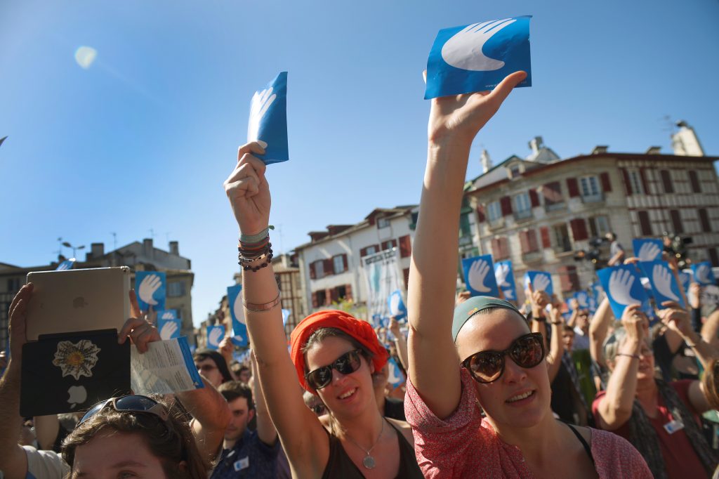 People hold up symbols of the "Artisans Of Peace" while attending a rally following the announcement of disarmament by arm...