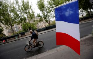 A cyclist passes a French flag on the eve of the French presidential election in Paris