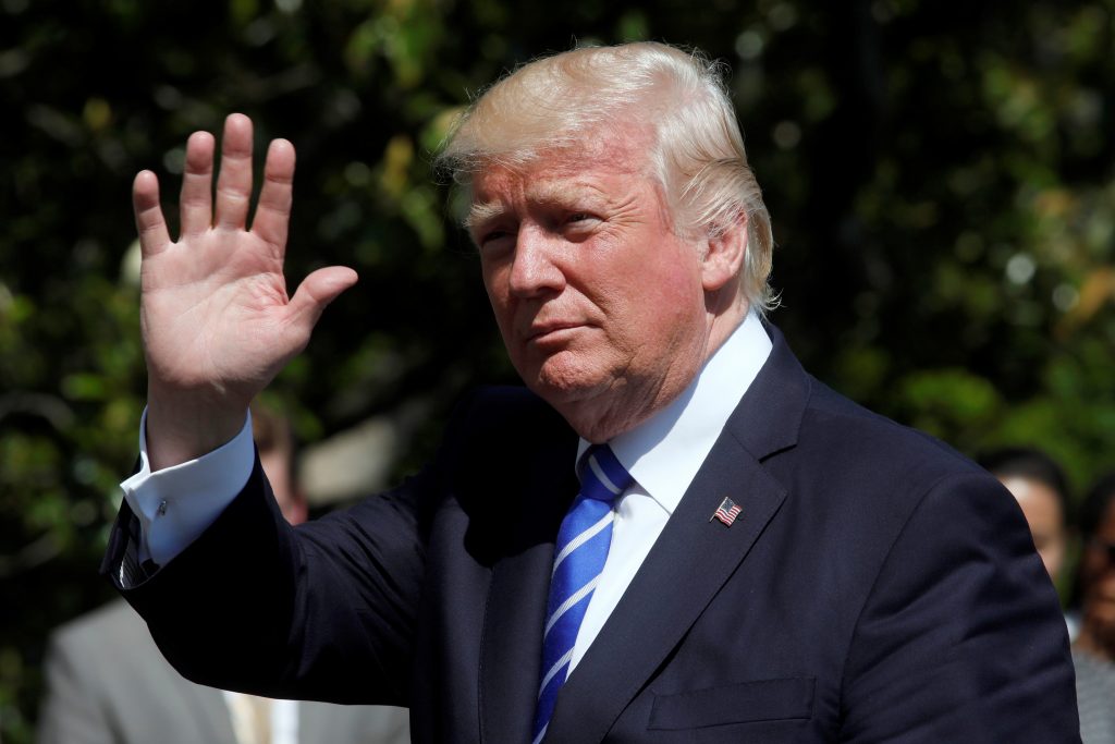 President Donald Trump waves as he walks on the South Lawn of the White House upon his return to Washington, D.C. Photo by...