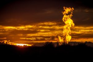 Flames from a flaring pit near a well in the Bakken Oil Field. The primary component of natural gas is methane, which is odorless when it comes directly out of the gas well. In addition to methane, natural gas typically contains other hydrocarbons such as ethane, propane, butane, and pentanes. Raw natural gas may also contain water vapor, hydrogen sulfide (H2S), carbon dioxide, helium, nitrogen, and other compounds. (Source: www.earthworksaction.org). As of July 2014, roughly 30 percent of the Photo by Orjan F. Ellingvag/Corbis via Getty Images