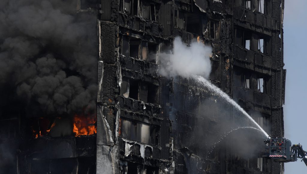 Firefighters direct jets of water onto a tower block severely damaged by a serious fire in north Kensington, West London o...