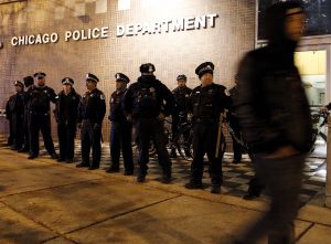 A protester walks past a line of police officers standing guard in front of the District 1 police headquarters in Chicago on Nov. 24, 2015. Photo by Frank Polich/Reuters