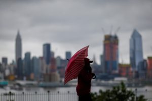A woman walks in a local park while clouds shroud the Empire State Building and the skyline of New York as it is seen from Weehawken, New Jersey, U.S. May 29, 2017. REUTERS/Eduardo Munoz - RTX384B4
