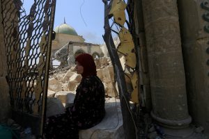 A displaced woman sits near the ruined Grand al-Nuri Mosque in the Old City of Mosul