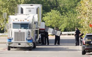 Police officers work on a crime scene after 10 undocumented immigrants being smuggled into the U.S. were found dead inside a sweltering 18-wheeler trailer parked behind a Walmart store in San Antonio. Photo by Ray Whitehouse/Reuters