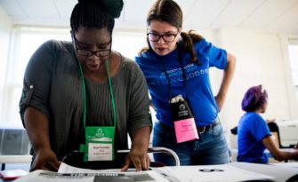 Angel Nalubega, senior at Antioch College, and Jeanne Kay, alumni relations coordinator, organize registration cards for at the Antioch College reunion weekend in Yellow Springs, Ohio Saturday, July 15, 2017. Eric Bates, an Antioch alumnus and the editor of New Republic, on the campus for a reunion with his fellow alumni. Bates calls Antioch a canary in the coal mine for much of the rest of higher education. Photo: Meg Vogel for The Hechinger Report