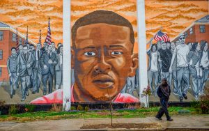 A man walks past a mural of Freddie Gray in the Sandtown-Winchester neighborhood of Baltimore, Maryland. Photo taken December 2015. Photo by Bryan Woolston/Reuters