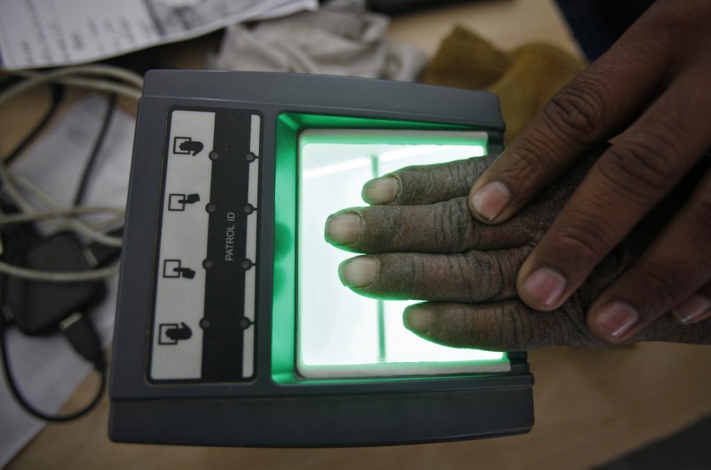A villager goes through the process of a fingerprint scanner for UID database system at an enrolment centre at Merta district in Rajasthan