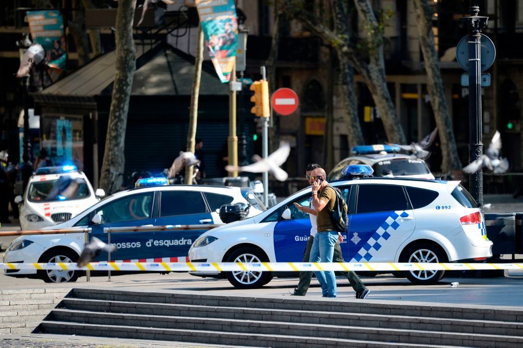 Plain-clothes policemen walk through a cordoned-off area after a van plowed into the crowd, injuring several persons on La...