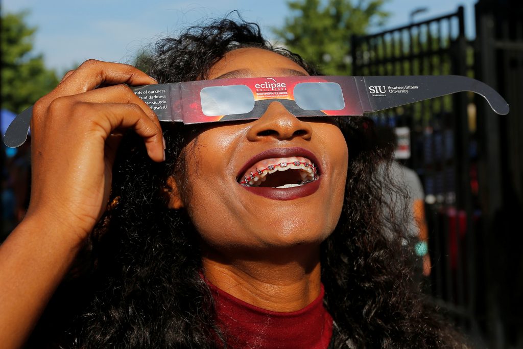 A cheerleader uses solar viewing glasses before the total solar eclipse at Southern Illinois University in Carbondale, Ill...