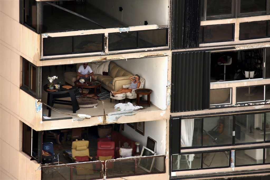 Two people sit in an apartment with a wall missing along the waterfront in San Juan. Nearly one week after Hurricane Maria...