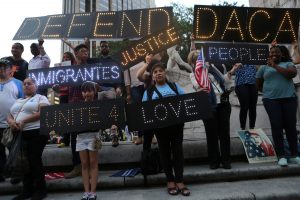 People hold signs against U.S. President Donald Trump's proposed end of the DACA program that protects immigrant children from deportation at a protest in New York City, U.S., August 30, 2017. REUTERS/Joe Penney
