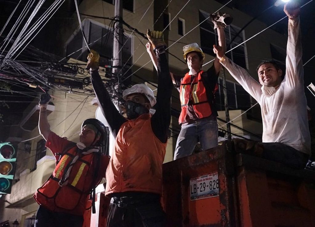 Rescuers at the site of a collapsed apartment building in Mexico signal for the crowd to be silent. Photo by William Brangham.
