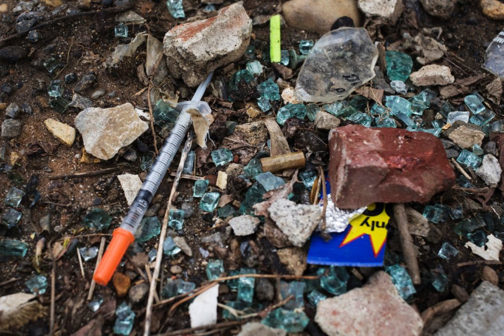Broken glass and a discarded needle are seen near a heroin encampment in the Kensington neighborhood of Philadelphia, Penn...