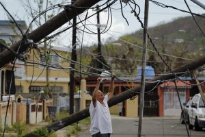 A resident uses a plastic bag to move downed power cables so he can drive underneath them in a neighborhood that has not seen recovery efforts following Hurricane Maria in Ceiba
