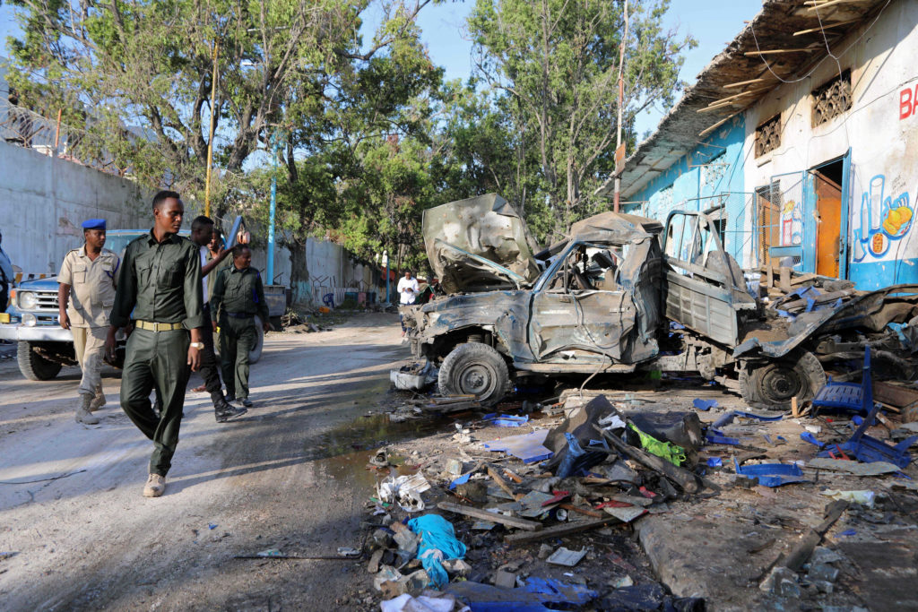 Somali security officers assess the scene of a suicide car bomb explosion, at the gate of Naso Hablod Two Hotel in Hamarwe...