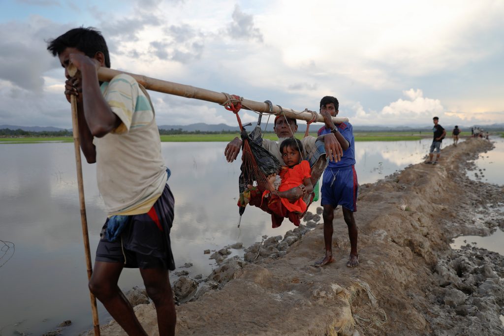 An elderly man and a child are carried as Rohingya refugees who fled from Myanmar make their way through the rice field af...